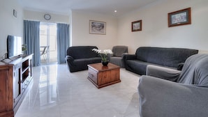 A living room with a sofa, a coffee table, and a TV stand.