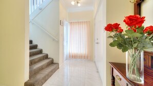 A staircase leading to a room with a wooden cabinet and a vase of red roses.