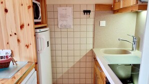 Eine kompakte Küche mit Mikrowelle, Kühlschrank, Spüle und Holzschränken.