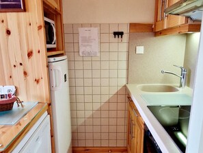 Uma cozinha compacta com micro-ondas, geladeira, pia e armários de madeira.
