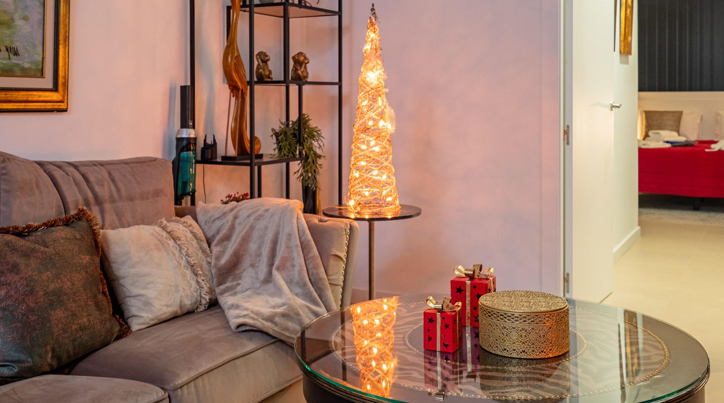 A living room with a glass coffee table, a tall decorative light, and a red gift box.