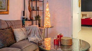 En stue med et sofabord i glas, en høj dekorativ lampe og en rød gaveæske.