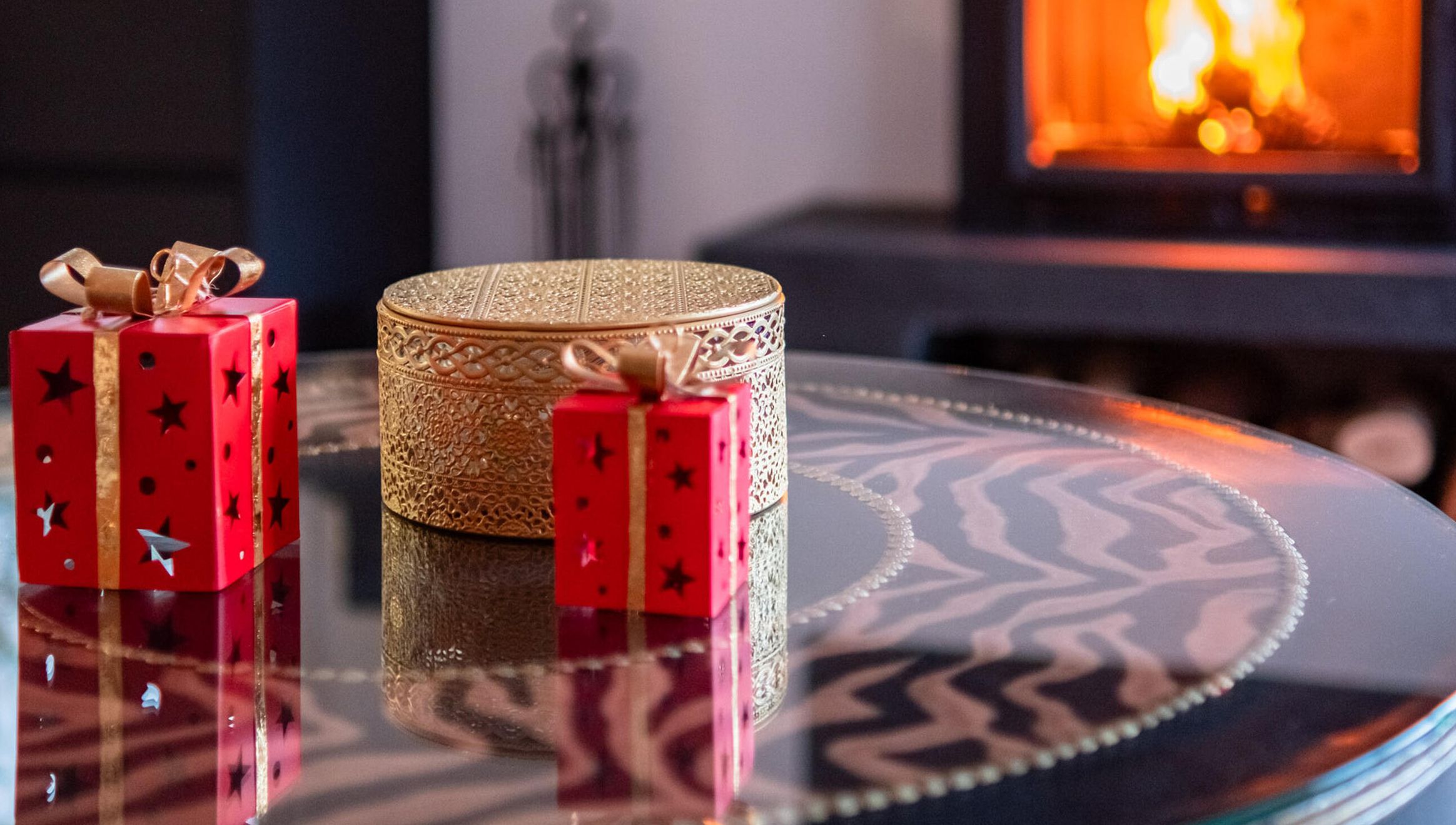 Una mesa con dos cajas de regalo rojas y un recipiente dorado decorativo.