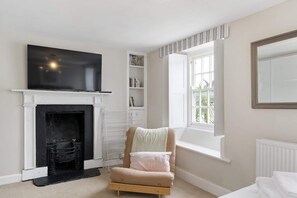Un dormitorio con chimenea, televisor, ventana con vistas y cama.