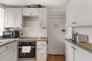 A compact kitchen with white cabinetry, a microwave, an oven, and a toaster.