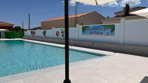Une piscine avec un mur blanc et une pancarte indiquant : « Piscine municipale de Policarp ».