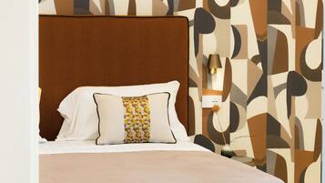Un lit bien fait, avec une tête de lit marron, un oreiller blanc orné d’un motif géométrique et une couvre-lit beige.