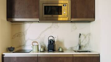 Una cocina equipada con microondas, hervidor y pileta.