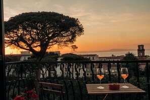 Un balcon avec une table, deux verres de vin et un bol de citrons.