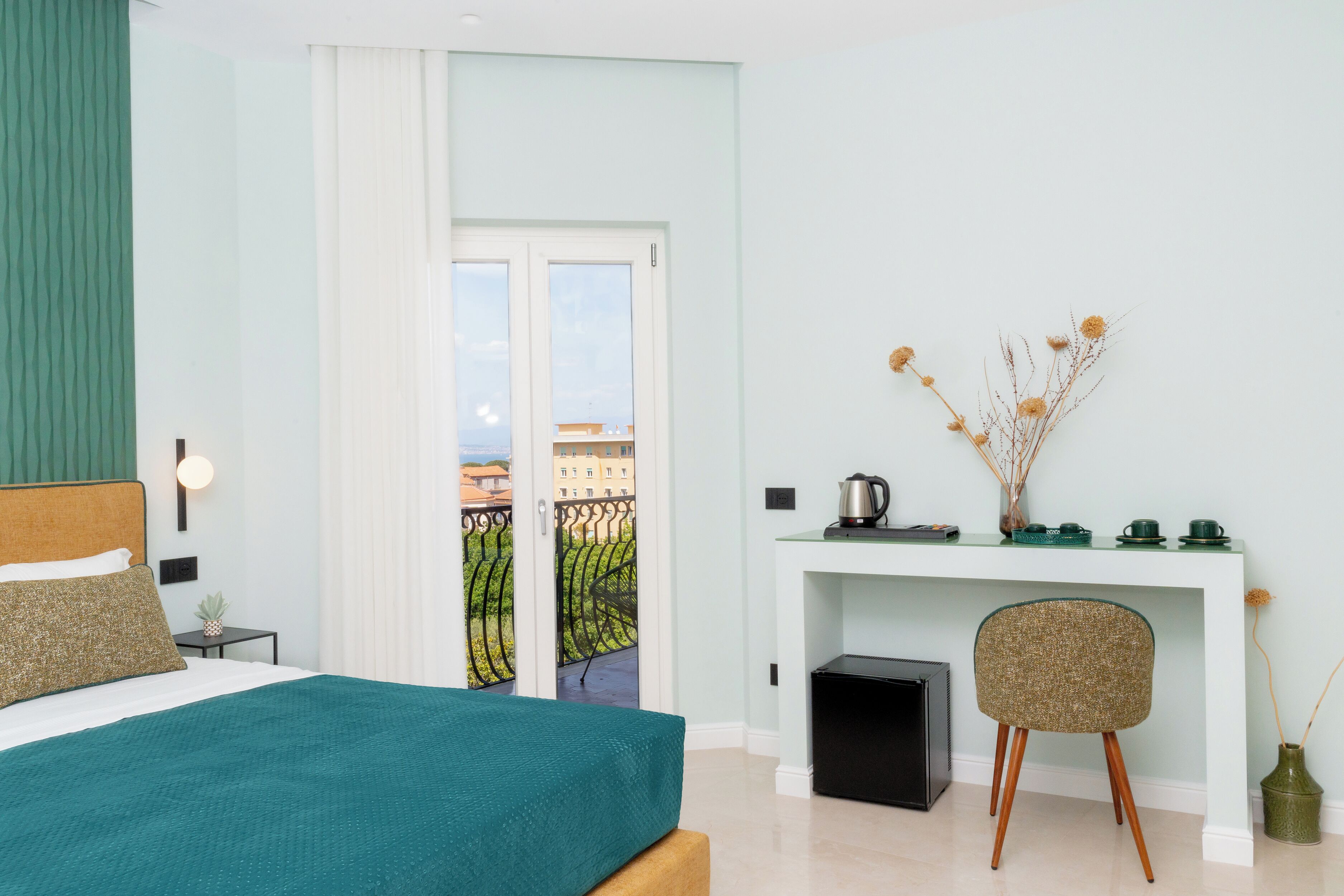 Une chambre à coucher avec un lit, un bureau et une chaise, une fenêtre et une vue sur des immeubles.