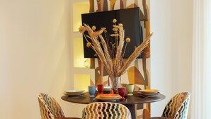 A dining area with a round table, colorful chairs, and a vase with dried plants. - Mermaids' Dream Sorrento (Sorrento)