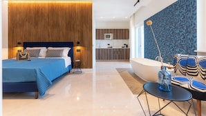 A modern bedroom with a large bed, a small table, and a bathroom with a bathtub. - Mermaids' Dream Sorrento (Sorrento)