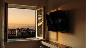 A room with a large window, a flat-screen TV mounted on the wall, and a chair. - Mermaids' Dream Sorrento (Sorrento)