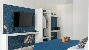 Un dormitorio con cama, televisión montada en la pared, armario y una silla.