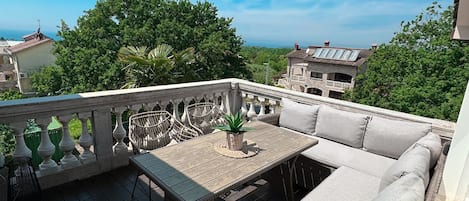 Un balcon doté de meubles en osier, d’une table et offrant une vue sur les environs.