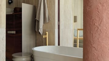 Un baño moderno con una bañera independiente, un tocador de madera y una toalla colgada en la pared.