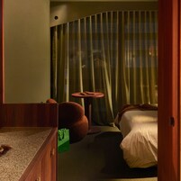 Una habitación de hotel con una cama, una mesa redonda y una silla verde.