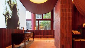 Un vestíbulo con un banco de madera, un mostrador de recepción y un amplio ventanal con vistas a edificios.