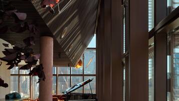 Um espaço amplo e interno, com um piano de cauda, janelas grandes e um design moderno no teto.