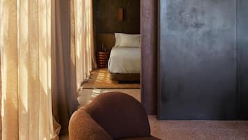 A modern bedroom with a bed, curtains, and a chair.