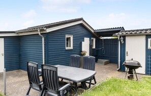 A patio area with a table and chairs, a barbecue grill, and a covered seating area.