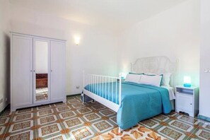 Cozy retreat with a white metal bed, patterned floor, and a wardrobe with a mirrored door.