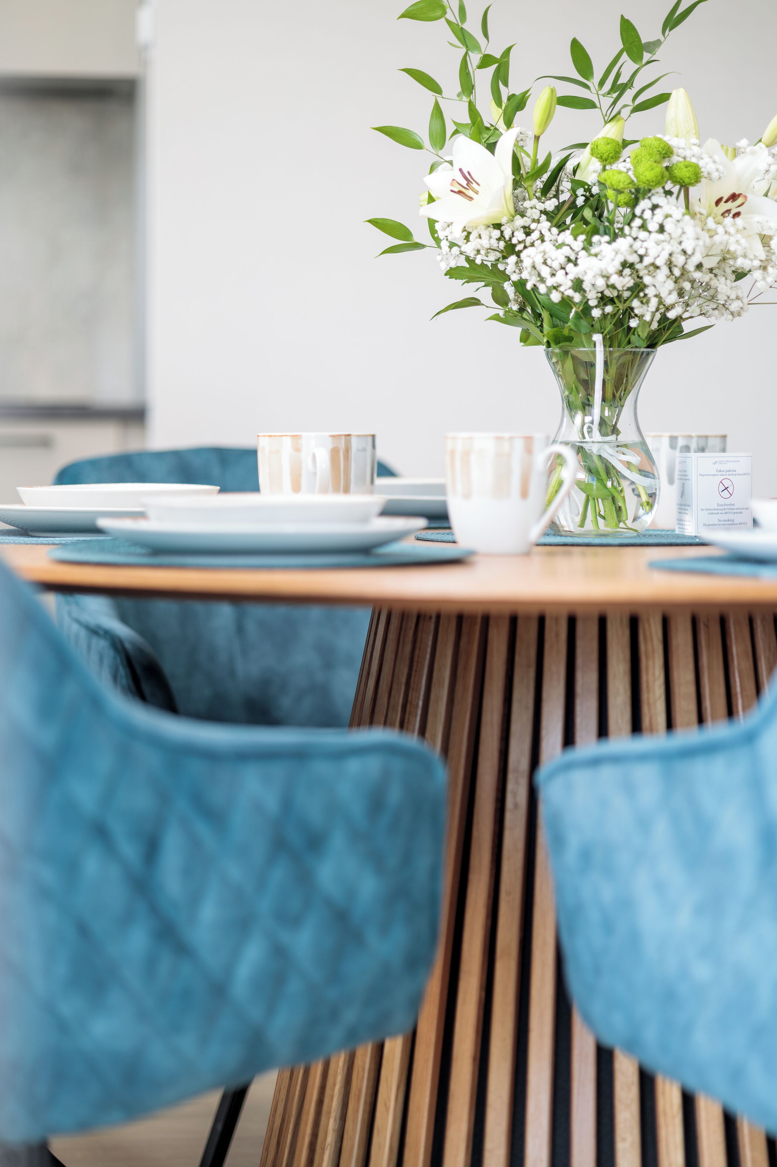 A dining table with a vase of flowers, plates, and cups.