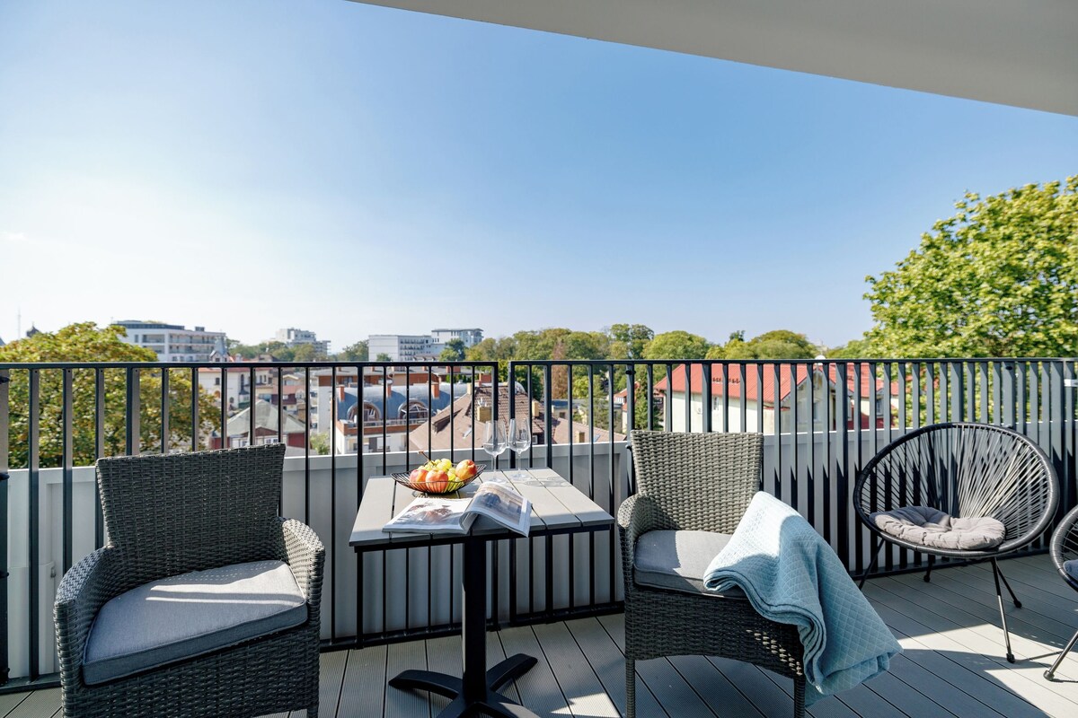 Ein Balkon mit Korbmöbeln, einem Tisch mit einer Zeitschrift und einer Obstschale.