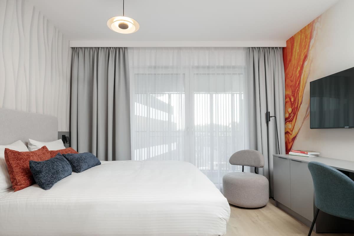 Une chambre d’hôtel moderne avec un grand lit, un bureau et une télévision.