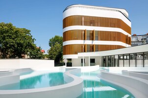 Un edificio moderno con fachada curva y zona de piscina con escalones blancos.