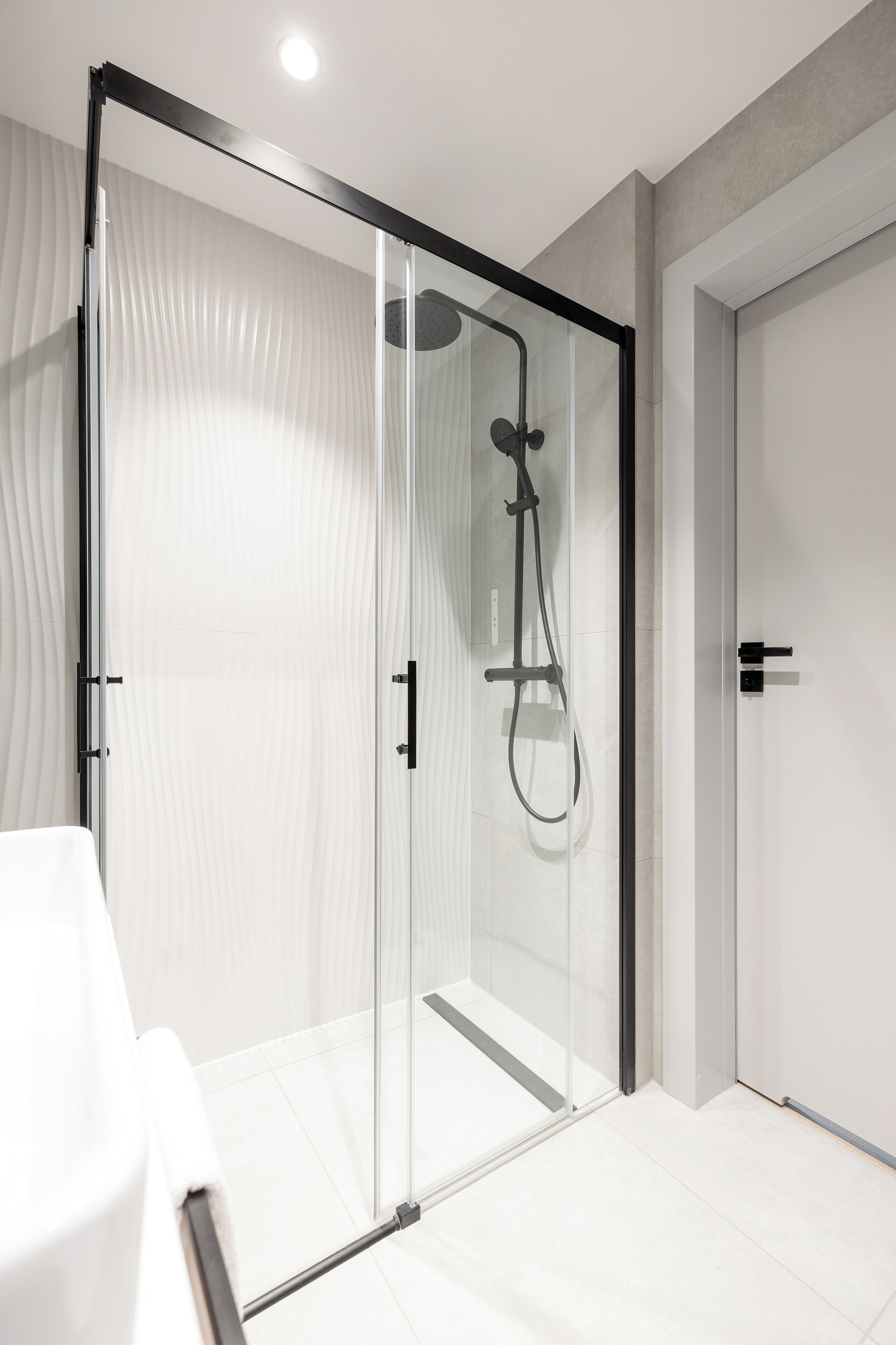 Une salle de bain moderne dotée d’une douche à parois de verre, de carreaux blancs et d’un design minimaliste.