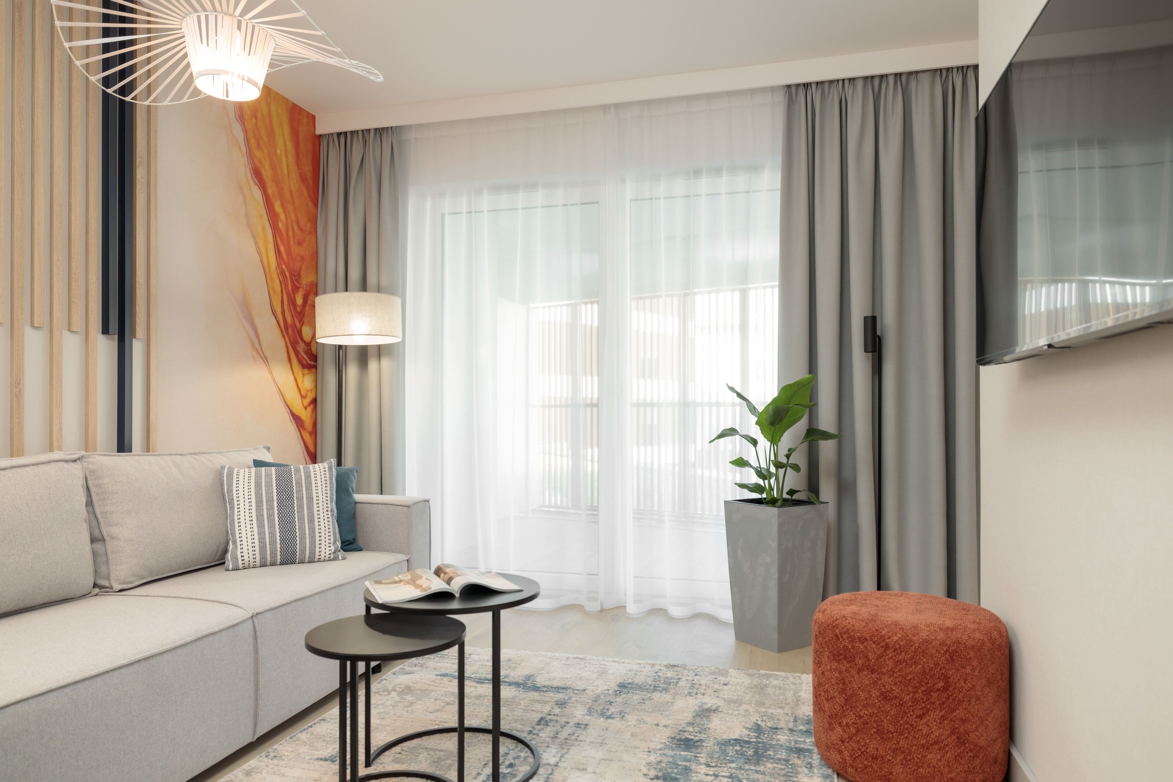 A modern living room with a sofa, a small round table, a lamp, and a potted plant.