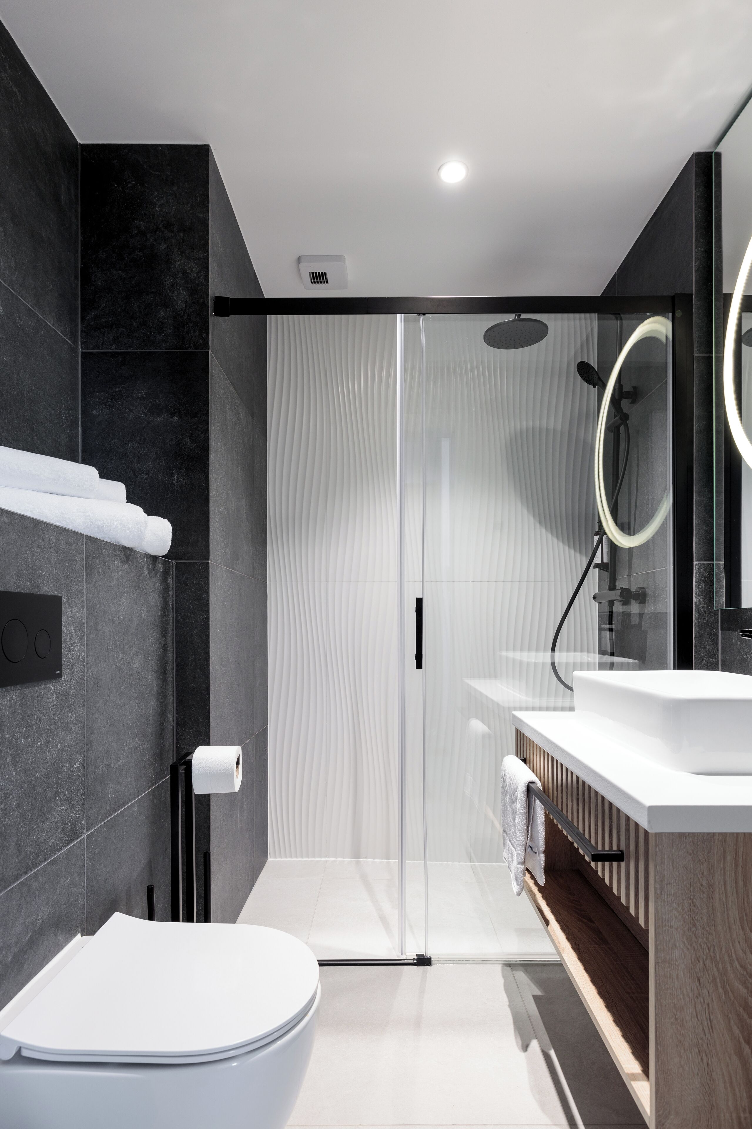 A modern bathroom with a toilet, bidet, and glass shower enclosure.