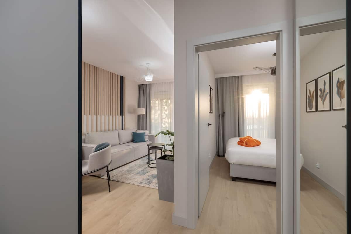 Une chambre d’hôtel moderne avec un canapé, un lit, une petite table et une plante en pot.
