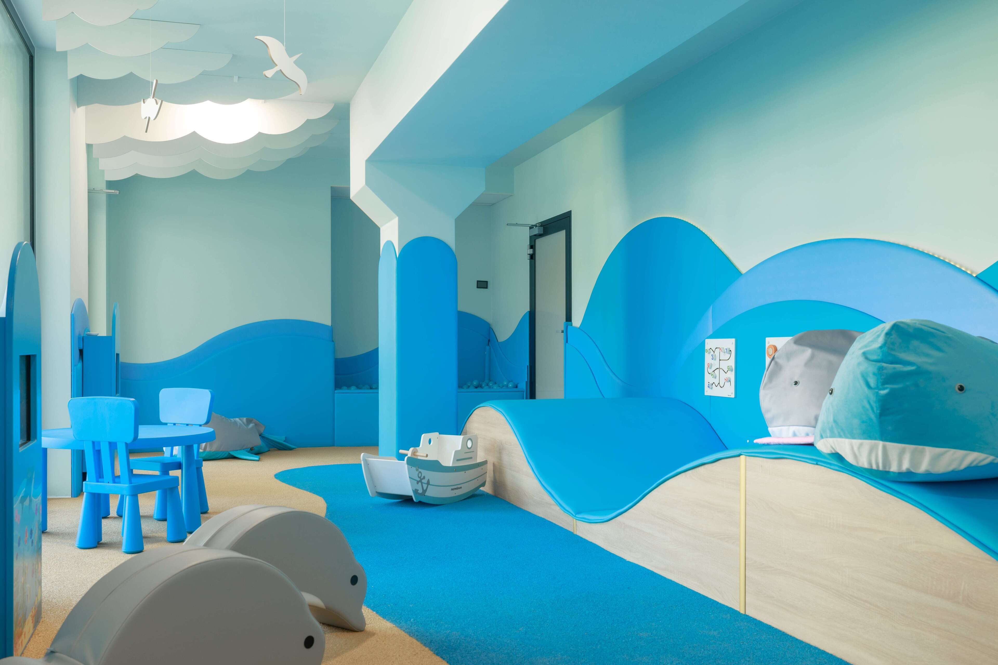 A children's play area with blue and white furniture, including a slide and a boat-shaped play structure.