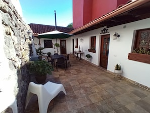A patio with a table and chairs, surrounded by potted plants and a stone wall. - Finca La Sirena Vacation Apartments - Apt. # 3 Garachico (San Juan del Reparo)
