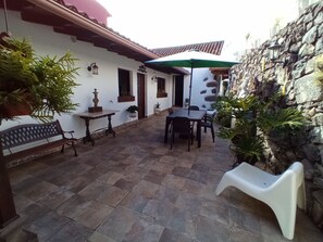 Relax in the serene courtyard, surrounded by lush greenery and a decorative stone wall.