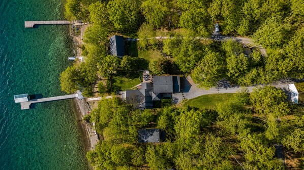 Luchtbeeld van een gelegenheid aan een meer, met een aanlegsteiger, een groot huis en omliggend groen.