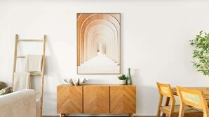 Een moderne woonkamer met een houten visgraatkast, een ingelijste abstracte kunstwerk, een houten eettafel met stoelen en een potplant.