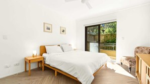 Een slaapkamer met een bed, nachtkastje en uitzicht op het omliggende landschap.