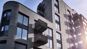 Een modern, meerlaags gebouw met een gebogen gevel, grote ramen en balkons.