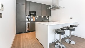 Een moderne keuken met donkere kastjes, een wit kookeiland en barstoelen.