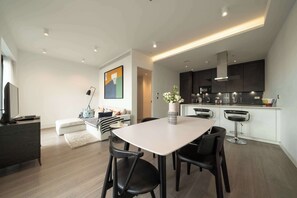A modern kitchen with dark cabinets, a stainless steel range hood, and a built-in microwave. - Beautiful, modern, light flat in Shoreditch (a) (Greater London)