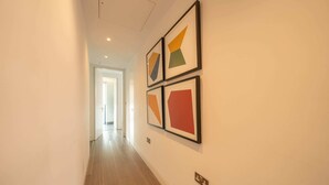 Ein Korridor mit Holzboden und weißen Wänden, der drei gerahmte Kunstwerke zeigt.
