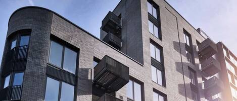 Un immeuble moderne à plusieurs étages, doté d’une façade incurvée, de grandes fenêtres et de balcons.