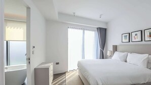 A modern hotel room with a large bed, a desk, and a window with curtains.