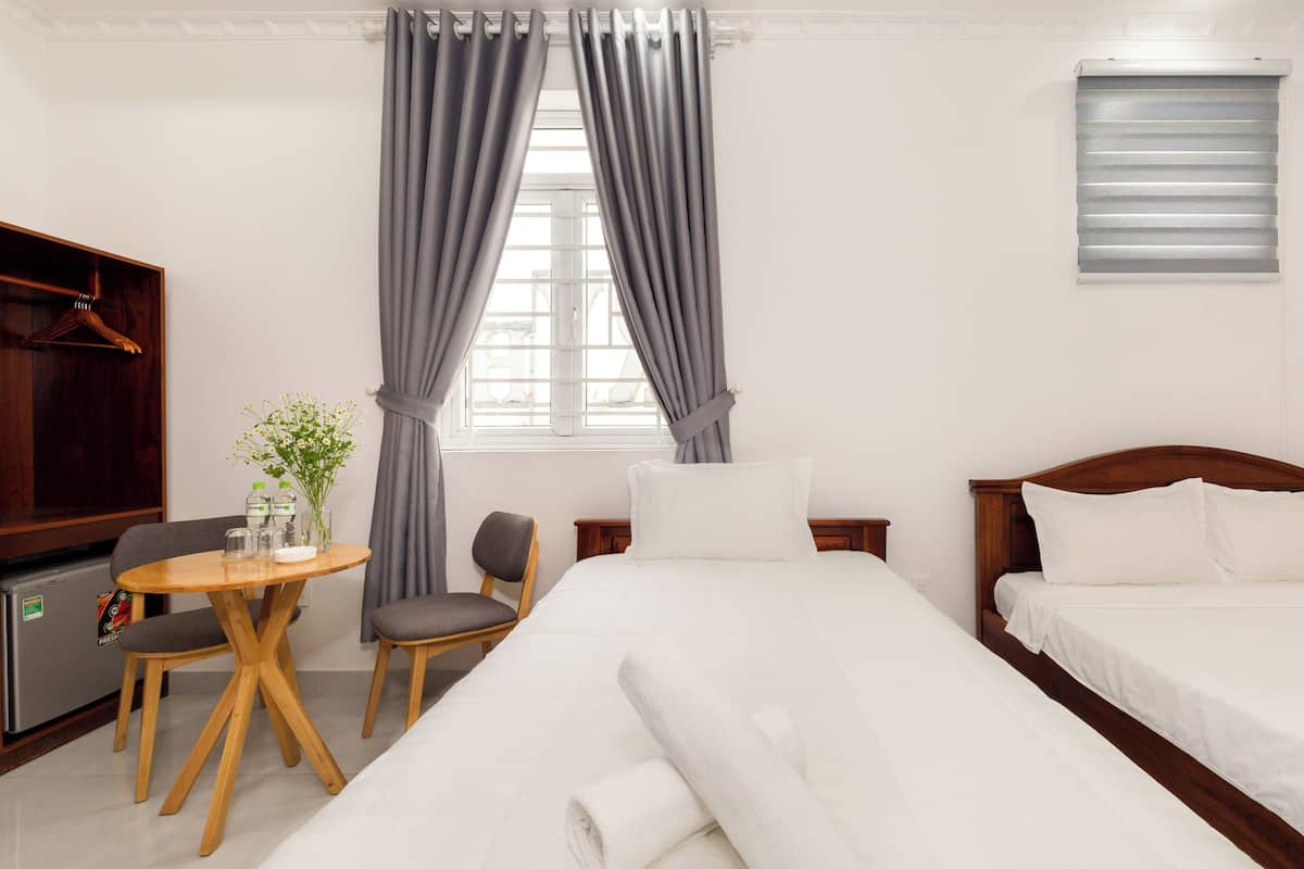 A hotel room with a bed, a desk with a chair, a TV, and a window with curtains.