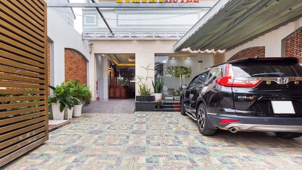 L'entrée d'un hôtel de luxe, avec une voiture noire garée sur le côté droit.