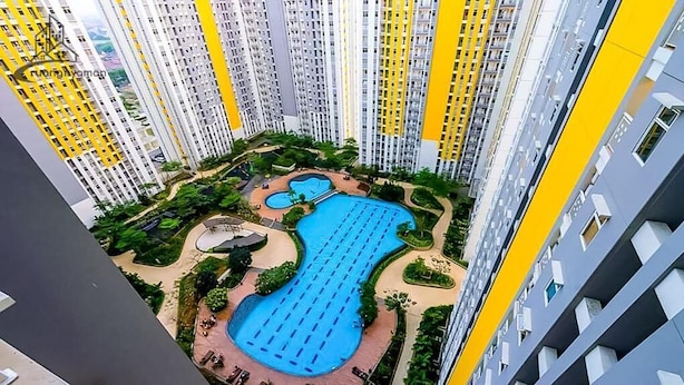 A high-rise residential building with multiple balconies, a central swimming pool, and surrounding greenery. - Capital O 93935 Kukami Rooms (Bekasi)