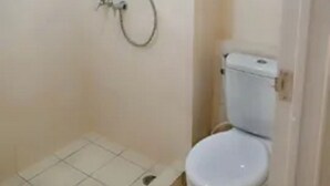 A small, enclosed bathroom with a toilet and a shower. - Capital O 93935 Kukami Rooms (Bekasi)